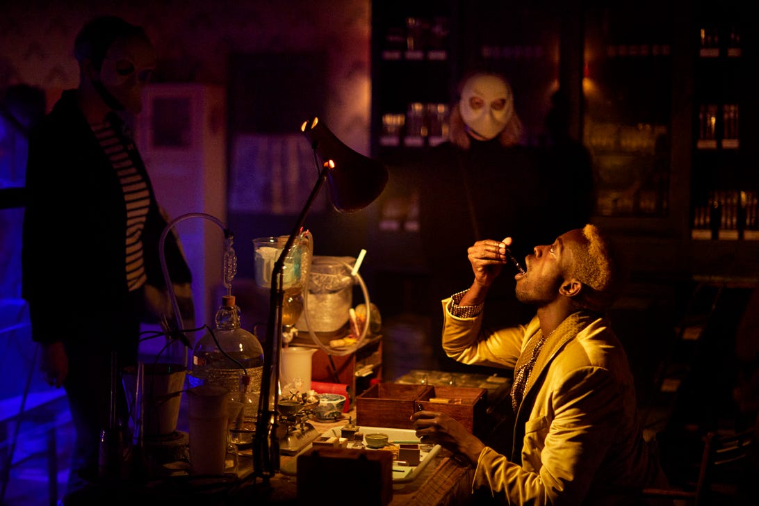 A masked audience member watches a performer in The Burnt City